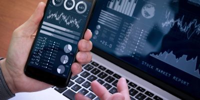 Investor analyzing stock market report and financial dashboard with business intelligence (BI), with key performance indicators (KPI).Businessman using smart phone with laptop computer.